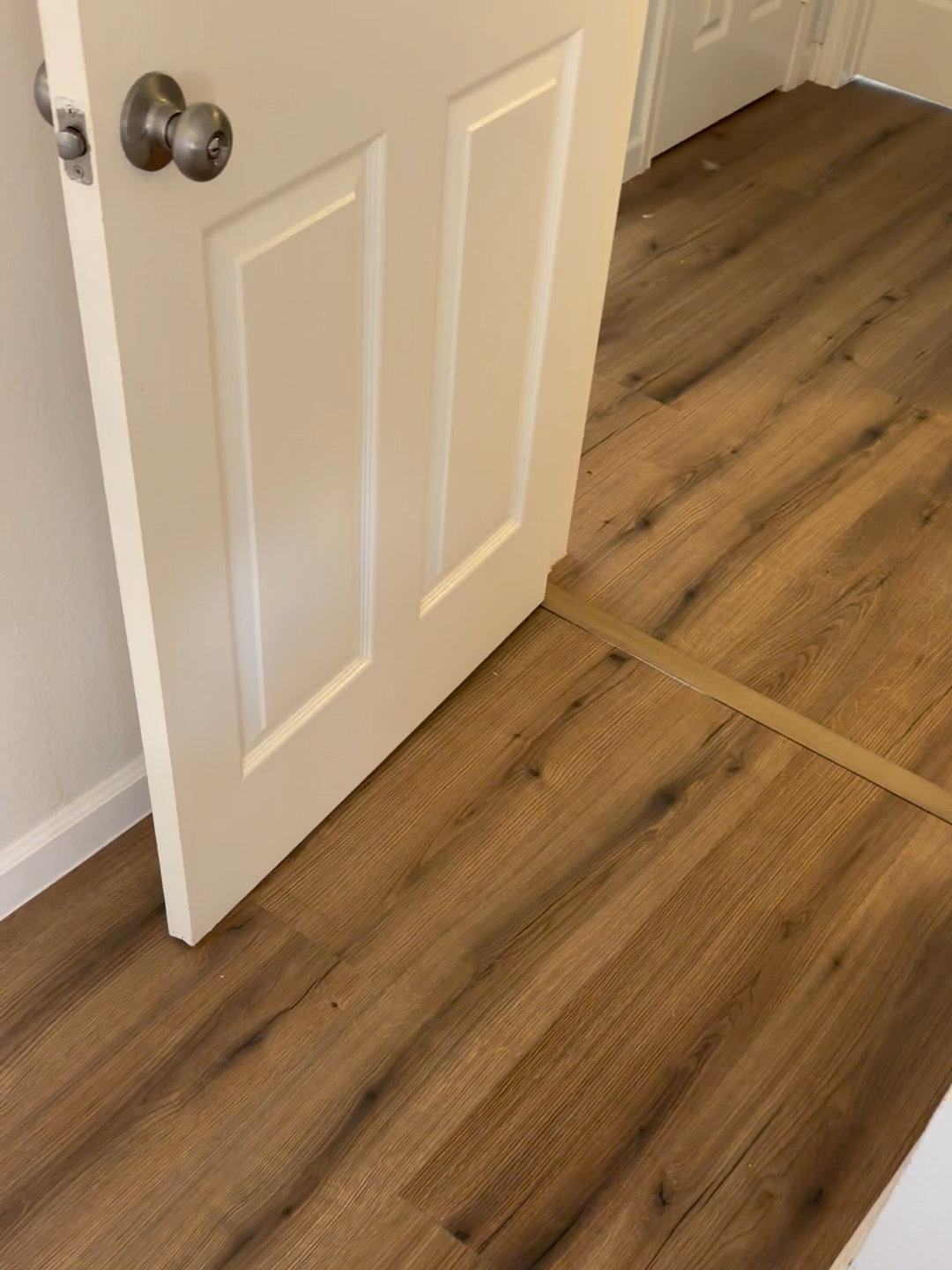 New plank flooring at a bedroom doorway with a clean transition strip