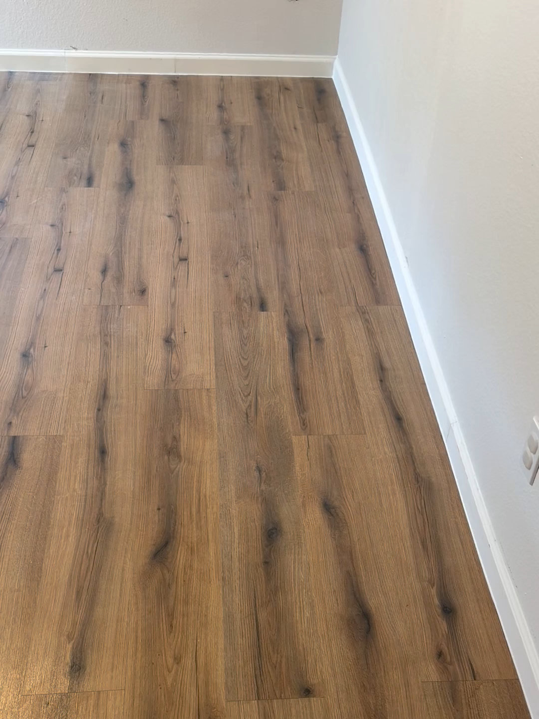 Long view of new wood-look plank flooring with white baseboards