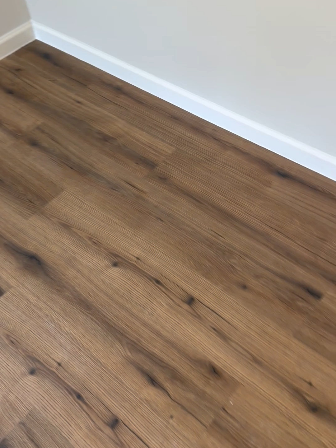 New plank flooring meeting fresh white baseboard at an inside corner