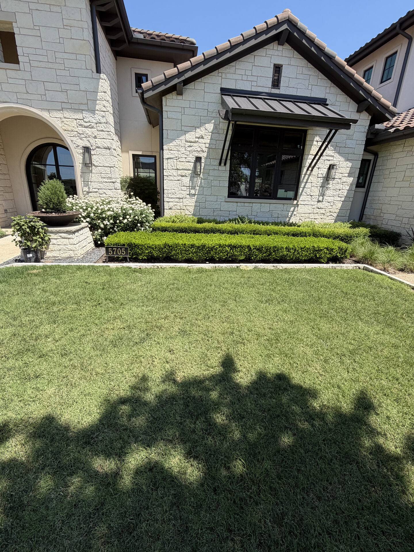 Manicured boxwood hedge and tidy lawn for a clean, welcoming entry.